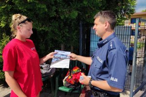 umundurowany policjant wręcza ulotkę informacyjna ratownikowi