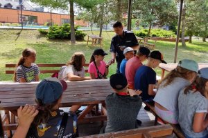 umundurowany policjant rozdaje ulotki dzieciom