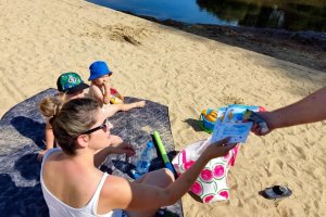 kobieta z dziećmi siedzi na kocu na plaży