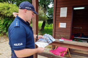 umundurowany policjant z ulotką informującą