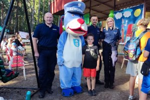 umundurowani policjanci z maskotka Sznupek oraz fotografującym się z nimi chłopcem