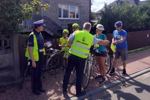 mężczyzna w kamizelce odblaskowej rozdaje elementy odblaskowe, obok stoi umundurowana policjantka