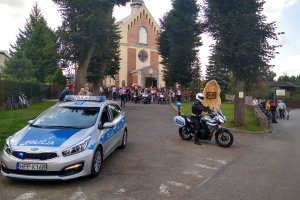 oznakowany radiowóz oraz policjant na motocyklu, w tle rowerzyści