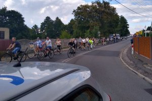 fragment oznakowanego radiowozu, w tle rowerzyści