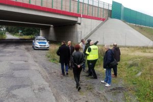 umundurowany policjant wraz z grupom osób dokonuje przeglądu infrastruktury drogowej