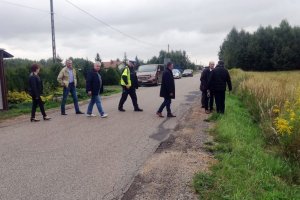 umundurowany policjant wraz z grupom osób dokonuje przeglądu infrastruktury drogowej