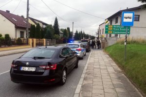 umundurowany policjant wraz z grupom osób dokonuje przeglądu infrastruktury drogowej