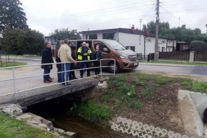 umundurowany policjant wraz z grupom osób dokonuje przeglądu infrastruktury drogowej