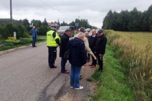 umundurowany policjant wraz z grupom osób dokonuje przeglądu infrastruktury drogowej