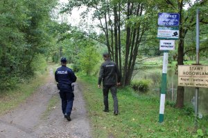 policjant i strażnik leśny idą przez las
