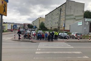 dzieci przechodzą przez przejście dla pieszych, obok policjanci i uczniowie z klasy mundurowej