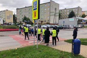 dzieci przechodzą przez przejście dla pieszych, obok policjanci i uczniowie z klasy mundurowej