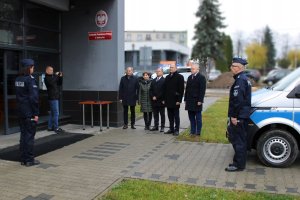 samorządowcy stoją przed budynkiem Komendy Policji w Kłobucku, obok umundurowany policjant oraz nowy radiowóz