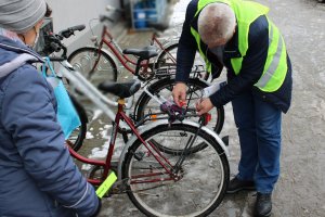 Mężczyzna w kamizelce montuje czerwoną lampkę do roweru