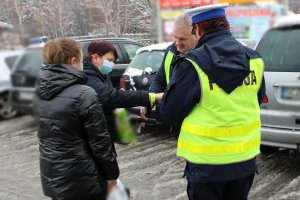 policjantka i mężczyzna w kamizelce przekazują odblaski dwóm kobietom