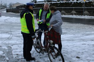 policjanta i mężczyzna w kamizelce rozmawiają z kobietą, która stoi przy rowerze