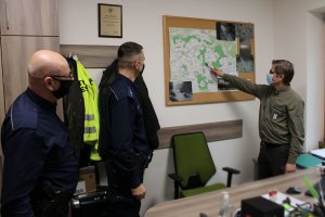 strażnik leśny pokazuje policjantom mapę