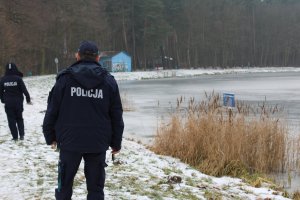 policjanci idą przy zamarzniętym zbiorniku wodnym