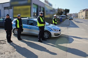 na zdjęciu widać oznakowany radiowóz przy którym stoją dwaj policjanci oraz dwie policjantki