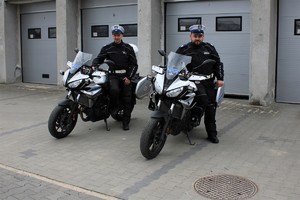 dwóch umundurowanych stoi przy służbowych motocyklach na placu komendy Policji w Kłobucku