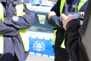 policjanci sterują dronem, w tle radiowóz