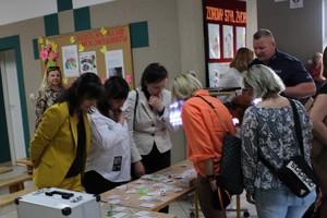 dzielnicowy pokazuje profilaktyczną walizkę rodzicom uczestniczącym w szkolnym zebraniu
