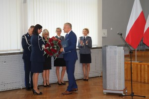 Mężczyzna w garniturze - burmistrz Kłobucka, wręcza kwiaty Pani Komendant