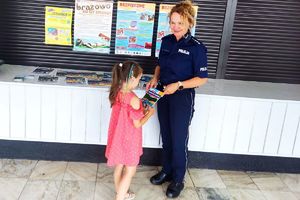 policjanta daje ulotkę dziewczynce w różowej sukience