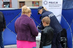 stoisko profilaktyczne policji, przy nim matka z dzieckiem