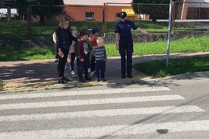 dzieci przechodzące przez jezdnię na pasach obok policjantka