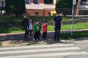 dzieci przechodzące przez jezdnię na pasach obok policjantka