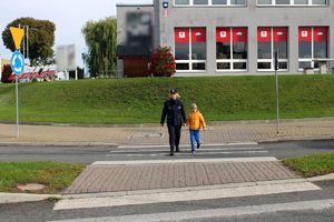 Policjantka przechodzi z chłopcem przez pasy.