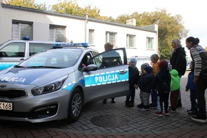 policjantka prezentuje przedszkolakom radiowóz na policyjnym parkingu