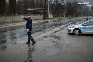 policjant zatrzymuje ręką pojazd. w tle radiowóz