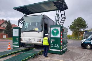 policjant kontroluje znajdujący się na mobilnej stacji autobus