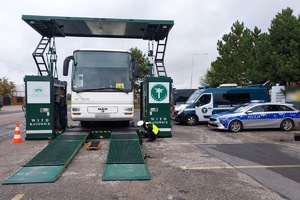 policjant kontroluje znajdujący się na mobilnej stacji autobus