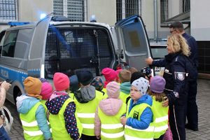 policjantka i policjant pokazują dzieciom radiowóz