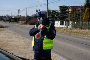 Policjant mierzy prędkość urządzeniem do mierzenia prędkości.