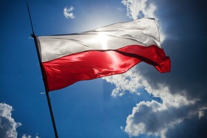 Biało-czerwona flaga Polski powiewająca na tle nieba.