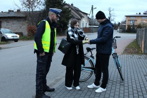 Zdjęcie przedstawia umundurowanego policjanta, pracownika Gminnej Komisji Rozwiązywania Problemów Alkoholowych oraz rowerzystkę z odblaskami.