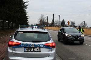 Zdjęcie przedstawia radiowóz oraz policjanta przeprowadzających badanie trzeźwości kierowcy.