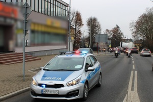 Zdjęcie przedstawia jadący radiowóz, za którym jadą motocykliści w przebraniach Mikołaja.