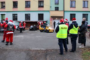 Zdjęcie przedstawia policjantów i motocyklistów w przebraniach Mikołaja na placu domu dziecka.