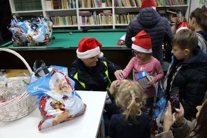 Zdjęcie przedstawia policjantkę, która zakłada dziewczynce opaskę odblaskową na rękę.