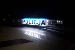 Zdjęcie przedstawia podświetlony napis Policja na dachu radiowozu.