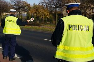 Zdjęcie przedstawia umundurowanych policjantów zatrzymujących pojazd do kontroli.