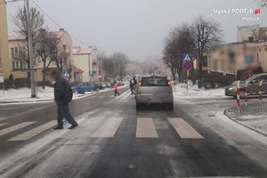 Zdjęcie przedstawia pieszego przechodzącego przez pasy w zimową pogodę.