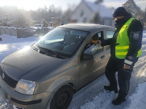 Zdjęcie przedstawia umundurowanego policjanta, który bada stan trzeźwości kierowcy.