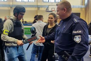 Zdjęcie przedstawia policjanta oraz ubranego w hełm i atrybuty policyjne chłopca oraz dziewczynę.