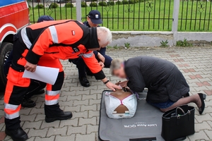 Zdjęcie przedstawia kierującą, która ćwiczy udzielanie pierwszej pomocy na fantomie oraz ratownika medycznego.